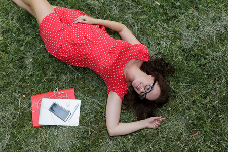 美丽的女人躺在草地上，周围是设备和小玩意。 顶部视图