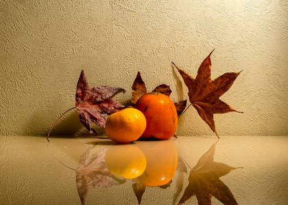 柿子和柑桔，玻璃表面有秋叶。 反射