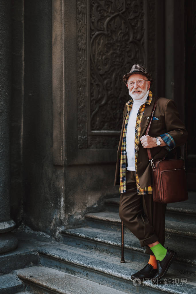 愉快的时尚老人站在台阶上