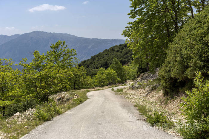 在阳光明媚的夏天观看农村狭窄的道路和山脉TzoumerkaEpirus希腊地区。