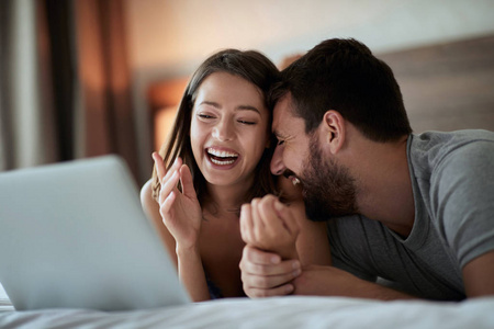 微笑的男人和女人早上在床上上网