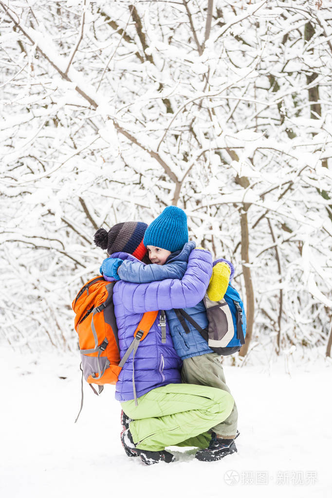 孩子拥抱妈妈. 一个男孩和他的母亲在冬季散步. 一个孩子吻他的母亲.
