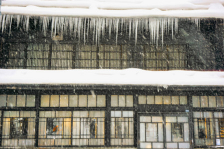 模糊和突出的焦点，向上看，雨滴是冰的屋顶上的房子，模糊的大雪下降前景。