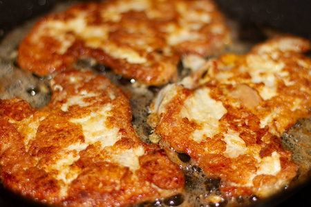 家里烤肉排的照片。 鸡蛋面糊和面包屑中的开胃脂肪猪排在煎锅里，用滚烫的葵花籽油煎。