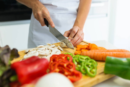 在家厨房里切新鲜蔬菜的健康年轻女人的手特写。