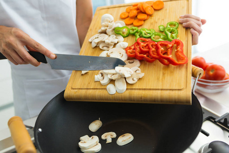 在家中厨房里把新鲜蔬菜放进锅里的健康女人的手。