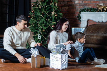 一个幸福的家庭围绕着一棵装饰好的圣诞树的圣诞照片。家庭庆祝新年