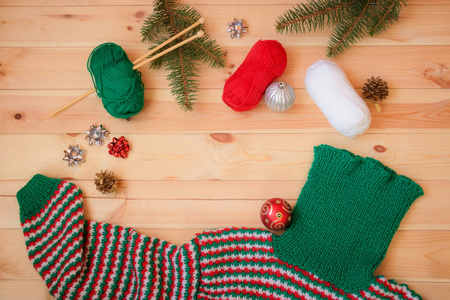 圣诞节和冬天。温暖的红，绿，白自制针织毛衣，冷杉树枝和圣诞球在木制背景。