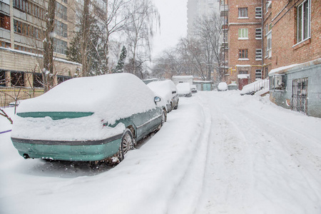 在停车场的冬季暴风雪中，车辆被雪覆盖。白雪覆盖的道路和城市的街道。