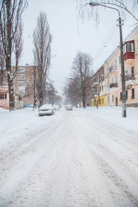 在停车场的冬季暴风雪中，车辆被雪覆盖。白雪覆盖的道路和城市的街道。