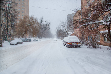 在停车场的冬季暴风雪中，车辆被雪覆盖。白雪覆盖的道路和城市的街道。