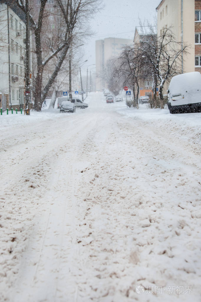 在停车场的冬季暴风雪中车辆被雪覆盖白雪覆盖的道路和城市的街道