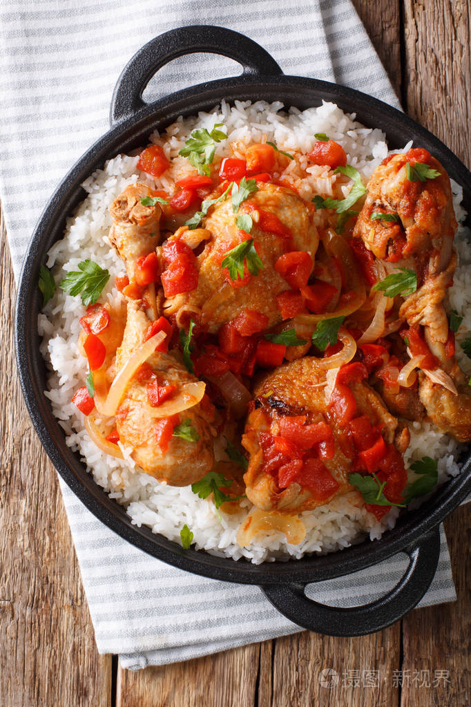 海地鸡在一个辛辣的番茄酱和米饭配菜特写在一个平底锅在桌子上.
