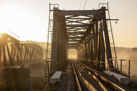 晨雾或烟雾中的铁路桥梁,阳光透过它照射背景.照片