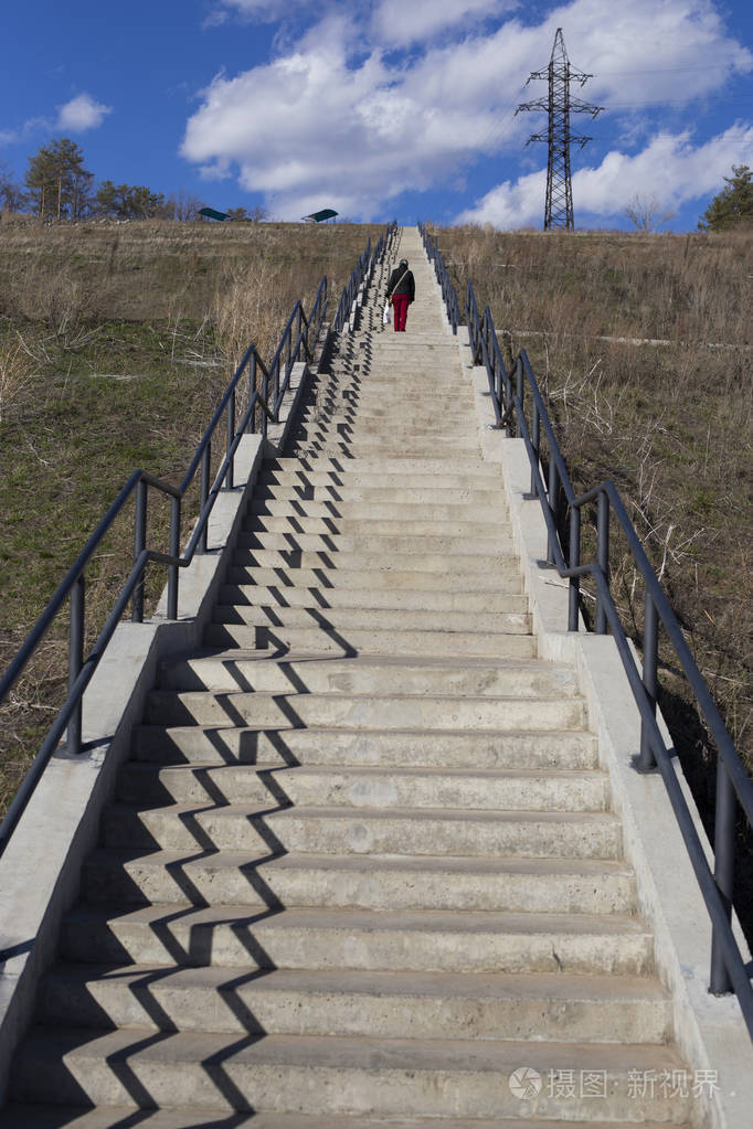 通往山的长楼梯上面是一根柱子一个年轻的女人穿着一件红色夹克