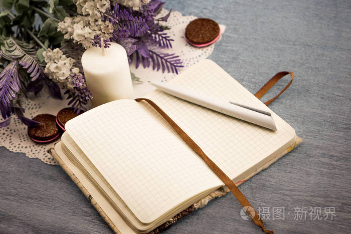 一本笔记本和一杯带牛奶的钢笔咖啡,放在一张白色餐巾纸上,旁边是两支