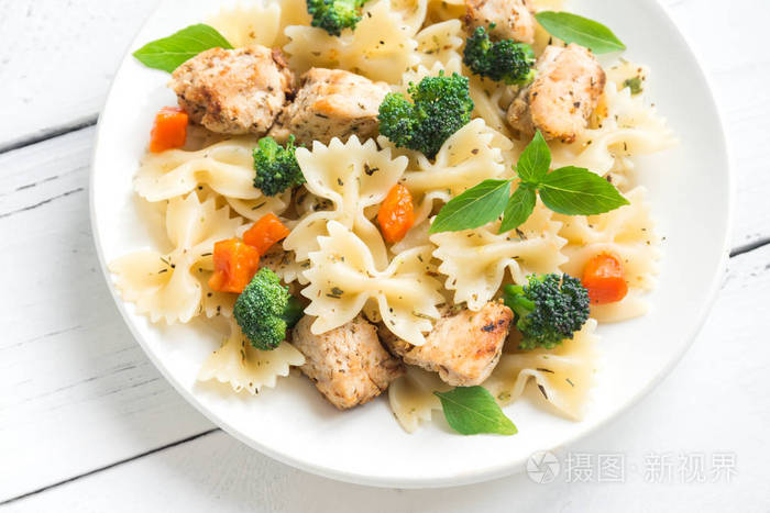 法法勒意大利面和鸡肉和蔬菜。 意大利面沙拉在白色木制背景复制空间。