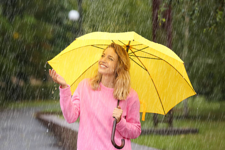 雨天公园里带黄色雨伞的年轻女子的肖像