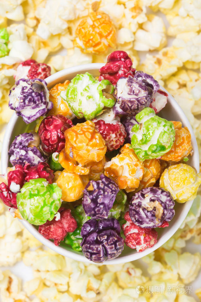 背景接近顶部的咸白色爆米花和带有彩色爆米花的纸杯