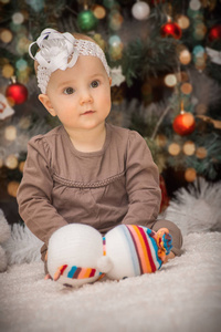 肖像小婴儿躺在圣诞树下的肚子上，背景是柔软的玩具