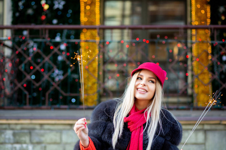 可爱的微笑金发女人戴着时髦的红色帽子在花环的背景下庆祝新年。 空的空间