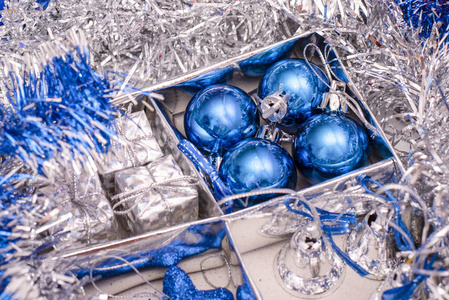 圣诞节玩具包括蓝色的星星, 蓝色的圣诞球, 银色的铃铛和礼品盒在盒子之间的银