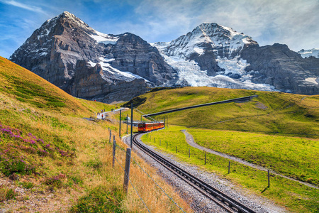 著名的电动红色旅游列车从KleineScheidegg的Jungfraujoch站欧洲之巅下来。 Eiger北面背景研磨，德