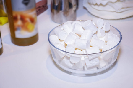 白色桌面上有棉花糖的玻璃碗。