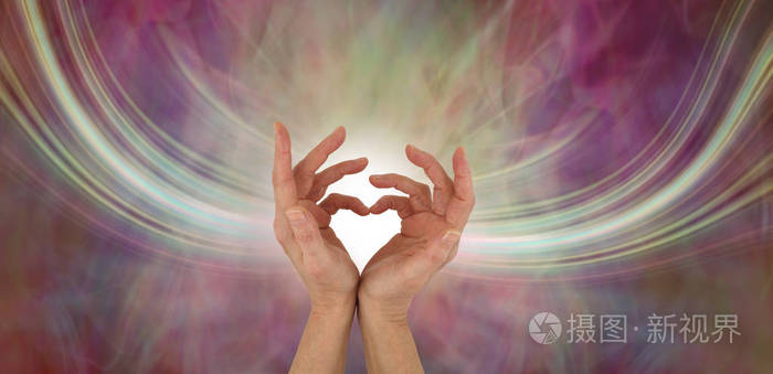 发出爱的振动,女性的双手创造一个心形,在温暖的五彩虚幻的背景和复制