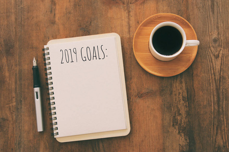 上图是2019年的目标清单，笔记本咖啡杯放在木桌上