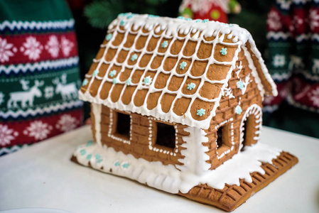 雪地里自制的圣诞姜饼屋。 背景中装饰的圣诞树。