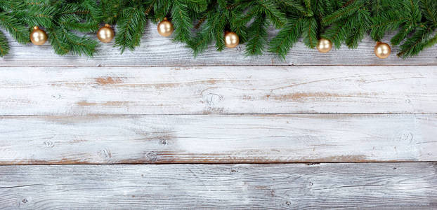 圣诞节的最高边界，常绿树枝和金色装饰在白色的老式木材上