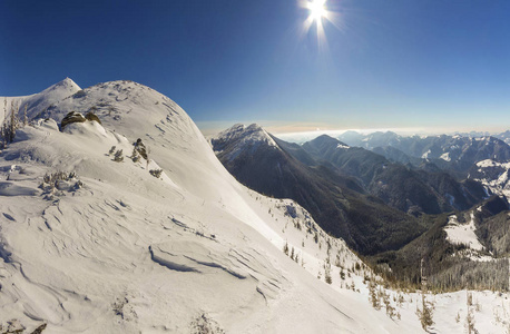 美丽的冬季景观。 陡峭的山坡与白色的深雪遥远的木本山脉全景延伸到地平线和明亮的阳光照射在蓝天复制空间背景。