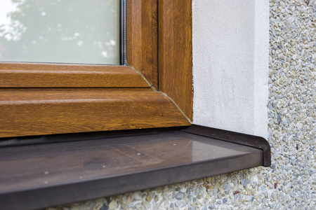 用新安装的棕色塑料窗和金属窗台关闭白色抹灰屋墙的细节.