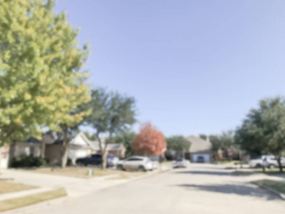 秋季季节，达拉斯德克萨斯州郊区模糊的抽象住宅区。 彩色的落叶沿着当地的街道，停着的汽车，云蓝的天空