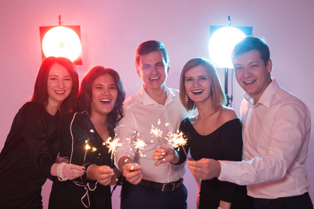 开心地庆祝。一群开朗的青年男女拿着火花。新年节假日和派对理念