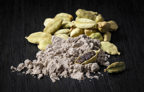  cardamom pods and ground coffee on a dark background