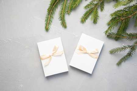 两个圣诞礼物在白色的盒子与灰色背景上的轻丝带。新年假期组成横幅。为您的文本复制空间