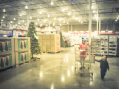 在美国德克萨斯州的批发商店购买人工圣诞树和圣诞配件的模糊运动客户。离焦抽象假日背景