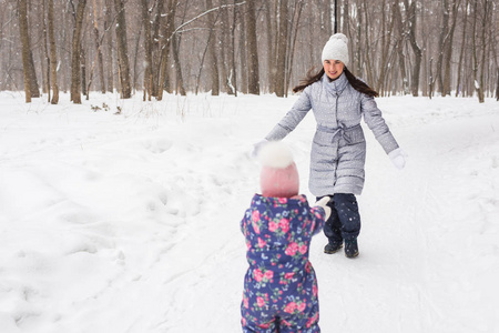家庭和自然概念母亲与女儿在冬季公园有乐趣