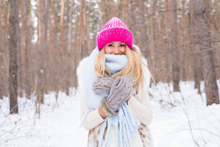 时尚和人的概念在冬季雪公园穿着白色外套和粉红色帽子的迷人的年轻金发碧眼的妇女的肖像