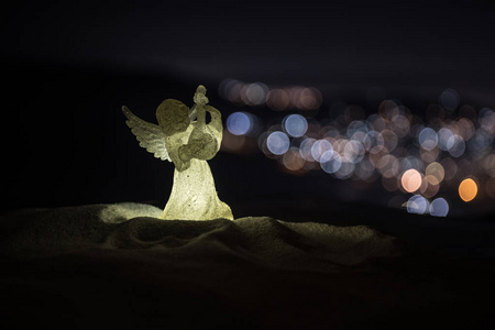 圣诞天使在模糊博克城灯在夜间背景。 白雪公主守护天使。 圣诞装饰
