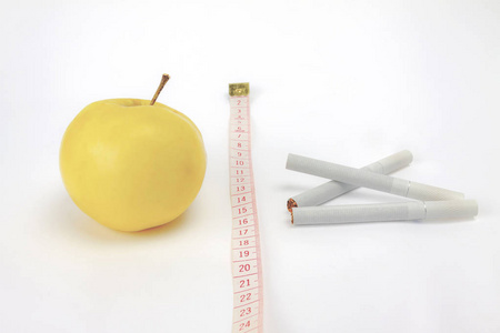 健康的生活方式概念。 在白色背景上用黄色苹果和香烟测量磁带。 隔离。