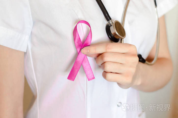 带听诊器的女医生留着一条粉红色的丝带。 乳腺癌检查概念