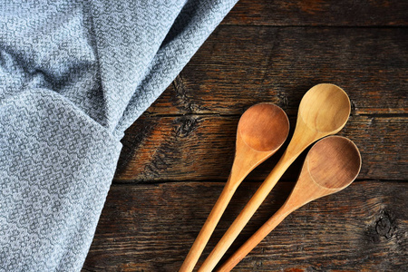 一张木制混合勺子和彩色桌布在老式乡村厨房桌面上的照片。