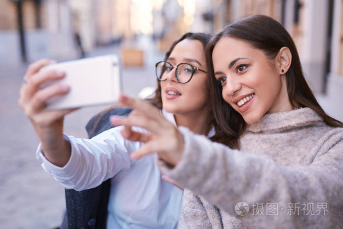 两个美丽的女人在城市的中心通过电话自拍