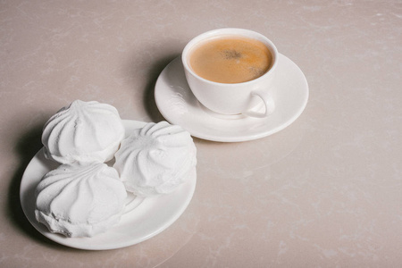 一杯新鲜咖啡美式咖啡和三个美味的甜点白色棉花糖在一个茶托特写。 复制空间