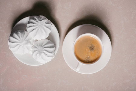 一杯新鲜咖啡美式咖啡和三个美味的甜点白色棉花糖在一个茶托特写。 复制空间