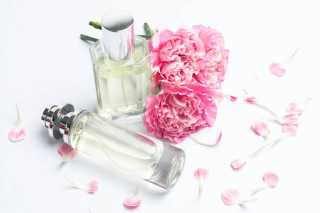 白色背景上美丽的香水瓶和粉红色康乃馨