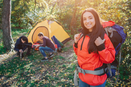 积极开朗的年轻女子在镜头前摆姿势.她看起来挺直了, 背着背包.